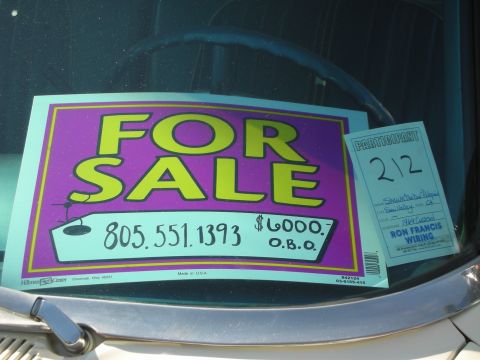 1998 Ford Crown Victoria - A sign in a car window advertises the vehicle for sale with a price and contact number.