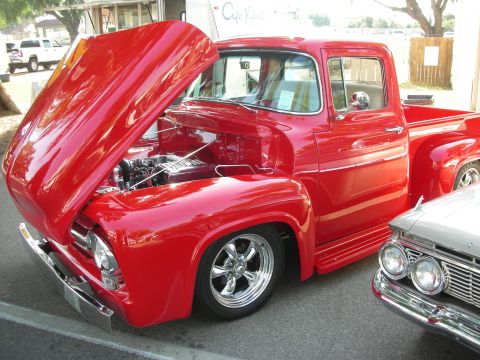 1998 Ford Crown Victoria - A classic red Ford F-100 pickup truck is displayed with its hood open, revealing the engine compartment.