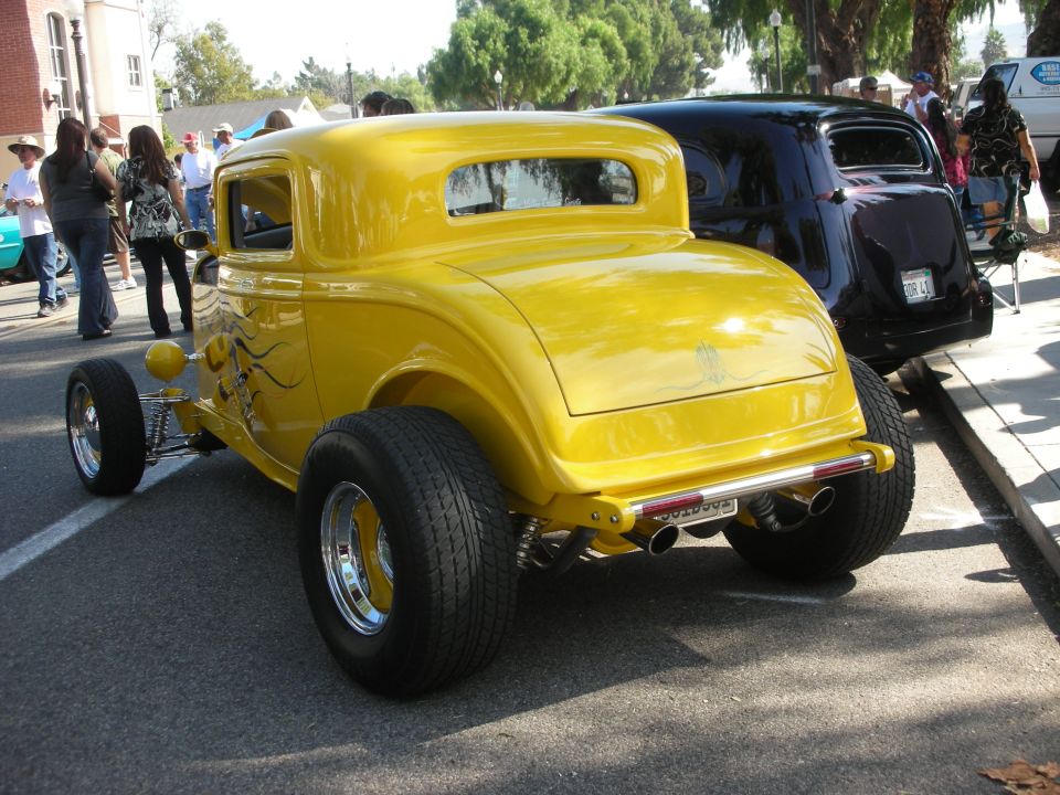 Yellow 1932 Ford five-window hot rod coupe, rear three-quarter view at street car show