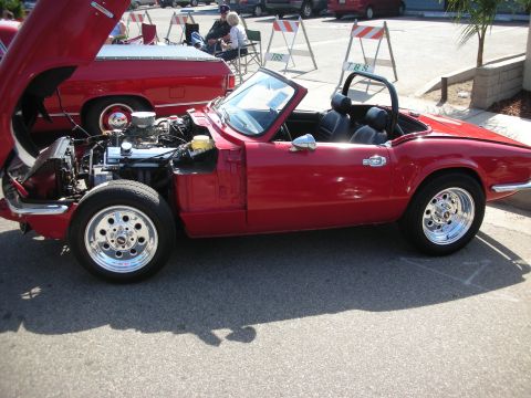 1998 Ford Crown Victoria - A red convertible is displayed with its hood open, revealing the engine and chrome wheels.