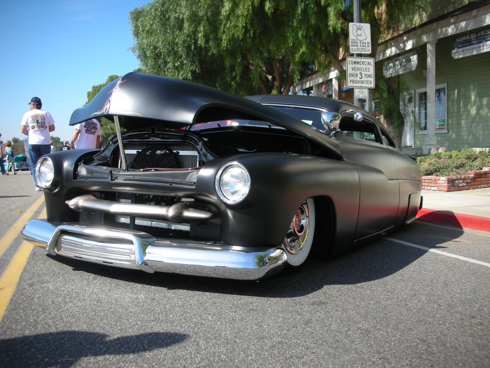 Front view of matte black chopped lead-sled custom coupe with hood open at show