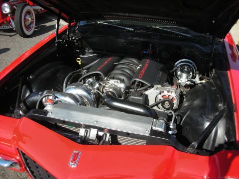 1998 Ford Crown Victoria - The engine bay of a red car features a turbocharger and Corvette engine components, with another vehicle partially visible.