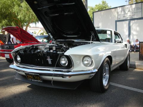 1998 Ford Crown Victoria - A white 1969 Ford Mustang is displayed with its hood open, parked next to another Mustang.