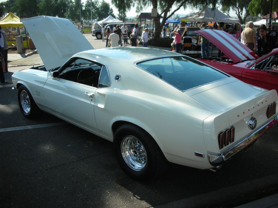 Rear three-quarter of white 1969 Ford Mustang fastback with hood open