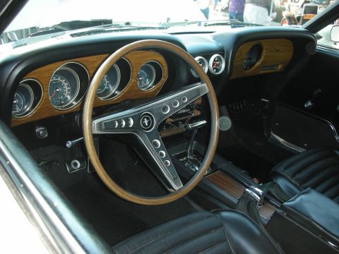 1998 Ford Crown Victoria - The interior of a 1969 Ford Mustang features a woodgrain dashboard and a classic steering wheel.