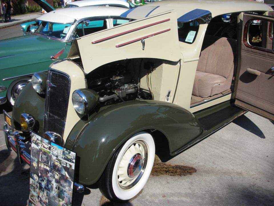 Cream and green 1930s sedan delivery with hood and door open at car show