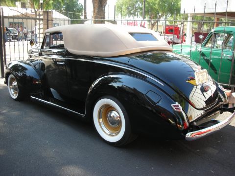 1998 Ford Crown Victoria - A classic black convertible with a tan soft top is parked outdoors, with another vehicle visible in the background.