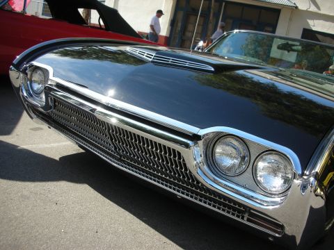 1998 Ford Crown Victoria - Front view of a black 1961 Ford Thunderbird convertible, with a red car behind it.