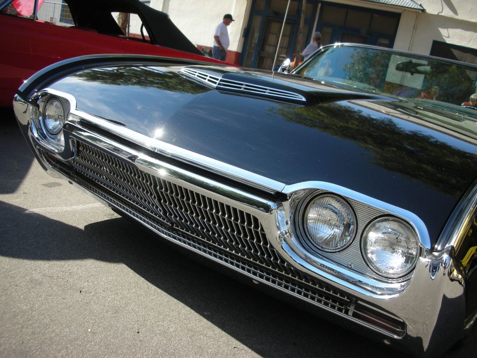 Close-up of a black classic car's chrome front grille and dual round headlights