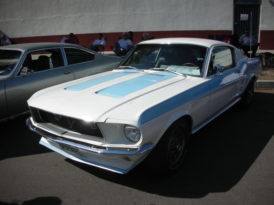 White 1967-68 Ford Mustang fastback with blue stripes at a car show