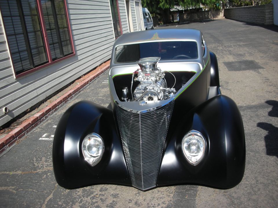 Front view of a black 1930s-style hot rod with exposed blower engine