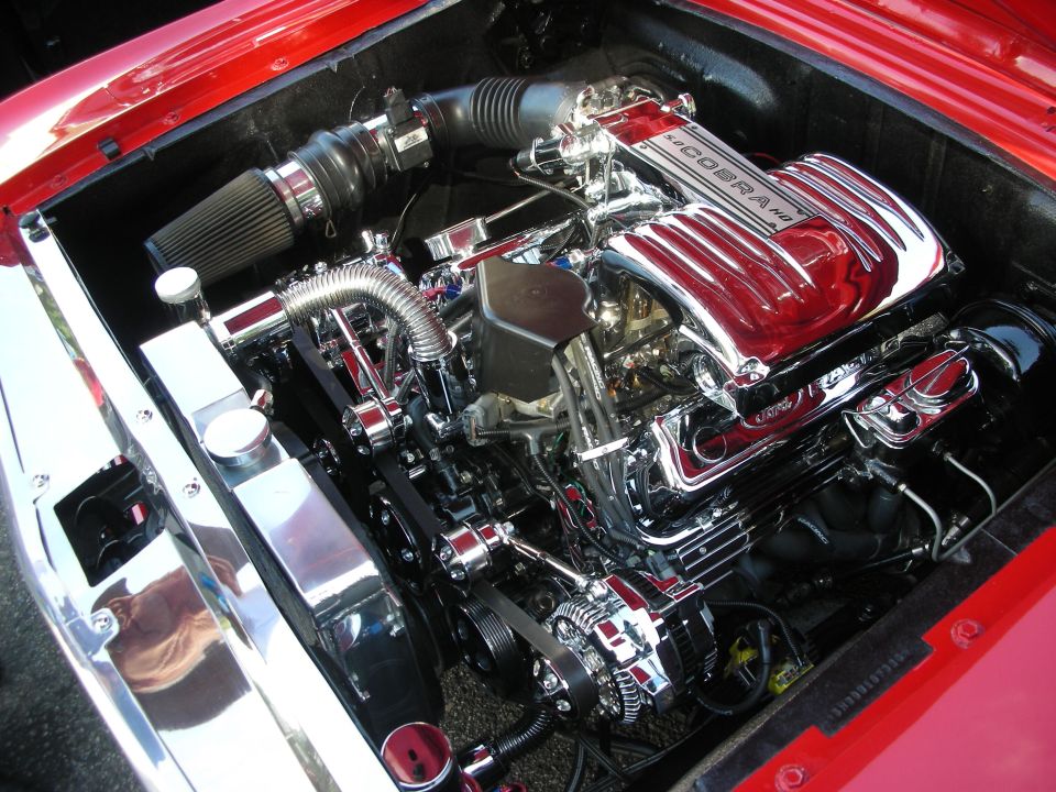 Chrome Cobra-labeled V8 engine with red covers in a red engine bay