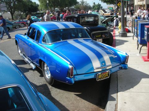 1998 Ford Crown Victoria - A blue custom car with silver racing stripes is parked on the street, with other vehicles and people in the background.