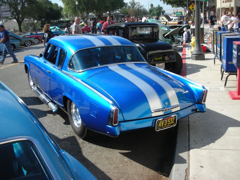Rear of a blue 1950s Studebaker coupe with silver stripes at a show
