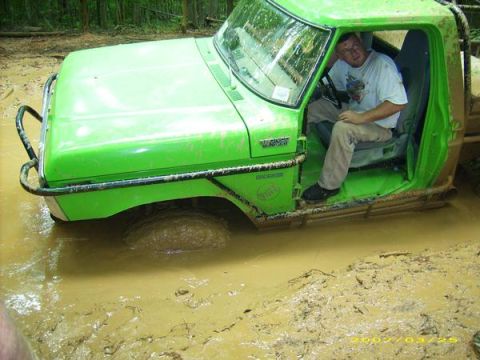 1978 Ford Bronco - A man sits in a bright green 1978 Ford Bronco that is deeply stuck in thick mud.