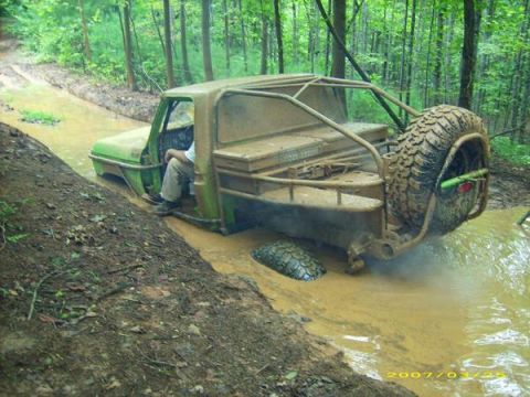 1978 Ford Bronco - This heavily modified off-road vehicle is stuck deep in the mud, with only its rear visible.