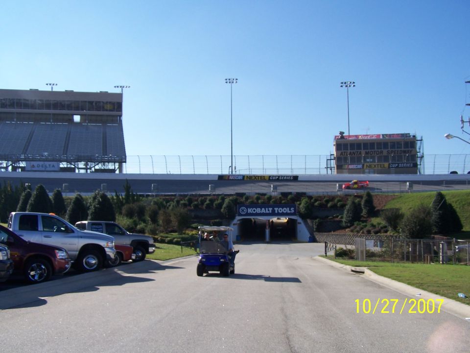 Atlanta Motor Speedway with grandstands, track, and a tunnel entrance. A golf cart is driving on the road