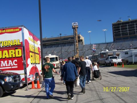 1979 Ford F-150 - A race track scene on October 27, 2007, a large National Guard truck, RVs, and spectators walking towards the stands.