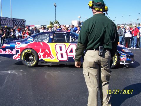 1979 Ford F-150 - A Red Bull sponsored NASCAR race car with the number 84 is seen on the track with spectators in the background.