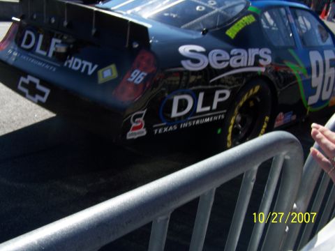1979 Ford F-150 - A black NASCAR race car with various sponsor decals, including Sears and DLP, is viewed from the rear.