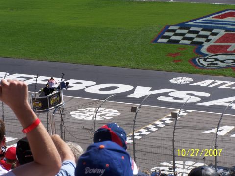 1979 Ford F-150 - Spectators watch a race from the stands, with the finish line and track markings visible in the foreground.