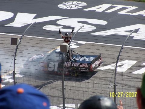 1979 Ford F-150 - A race truck celebrates victory on the track, with smoke billowing from its tires and the driver standing triumphantly on the roof.