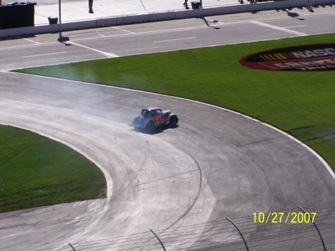1979 Ford F-150 - A stock car drifts around a turn on a race track, leaving a trail of smoke.