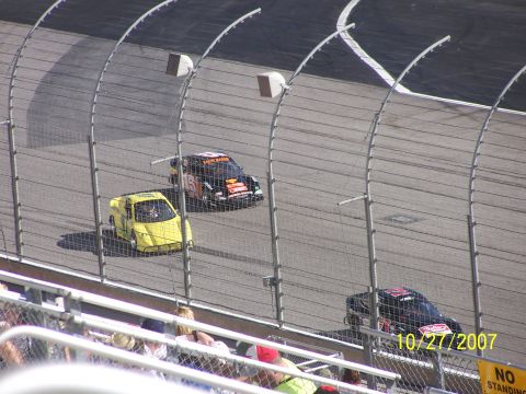 1979 Ford F-150 - Stock cars compete on a race track, with a yellow car leading two black cars.