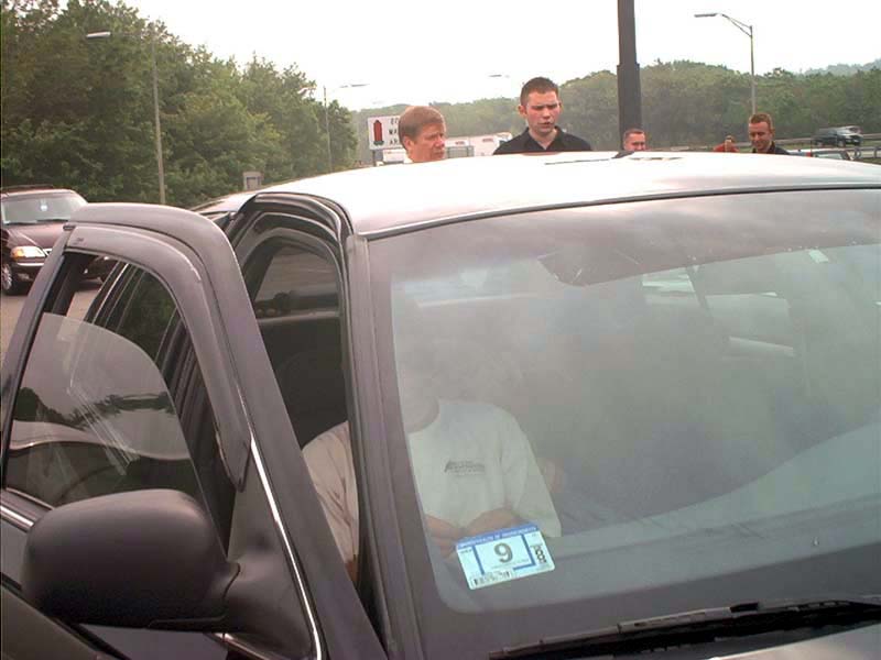 Black Ford Crown Victoria with open driver's door, showing interior and a person inside. A sticker is on the windshield