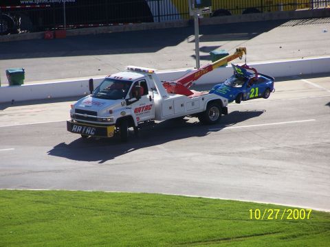 1979 Ford F-150 - A tow truck removes a damaged race car from a track.