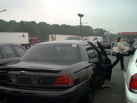 2000 Ford Crown Victoria - Rear view of a black 2000 Ford Crown Victoria with the driver's door ajar, parked in a lot with other vehicles.