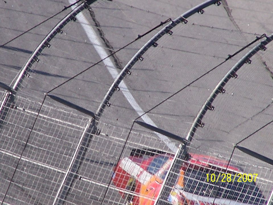 Race car on track, seen through a fence. Date stamp reads 10/28/2007