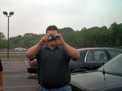 2000 Ford Crown Victoria - Man takes a photo of a 2000 Ford Crown Victoria parked outdoors.