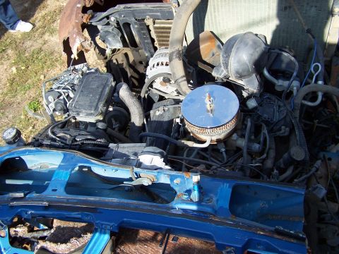 1995 Ford Bronco - The engine bay of a severely damaged vehicle is visible, with many parts rusted and exposed.