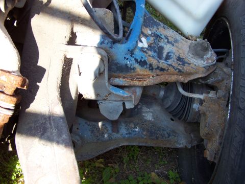 1995 Ford Bronco - Close-up view of heavily rusted vehicle suspension components, including a tire.