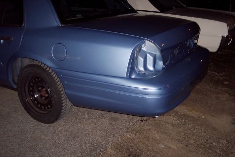 2001 Ford Crown Victoria - The rear of a blue 2001 Ford Crown Victoria is visible, parked next to another vehicle.