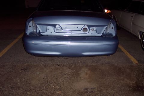 2001 Ford Crown Victoria - Rear view of a blue 2001 Ford Crown Victoria, missing its taillights, parked next to another vehicle.