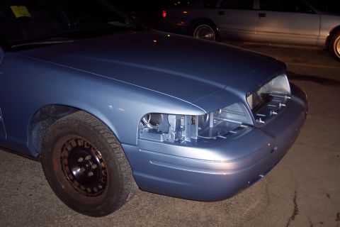 2001 Ford Crown Victoria - Front view of a blue 2001 Ford Crown Victoria showing damage to the headlight assembly and a steel wheel.