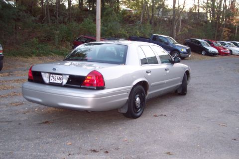 2001 Ford Crown Victoria - A silver 2001 Ford Crown Victoria is parked in a lot with other vehicles visible in the background.