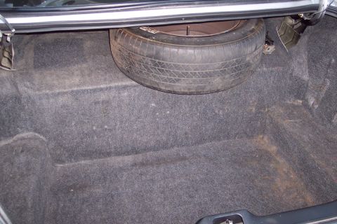 2001 Ford Crown Victoria - The trunk interior shows a spare tire and carpet lining. No identifying marks are visible to confirm the vehicle's make or model.