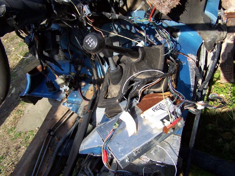 Vehicle interior with exposed wiring harness and control modules. Gear shift knob visible