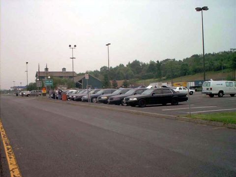 2000 Ford Crown Victoria - A row of sedans are parked in a lot next to a building under an overcast sky.