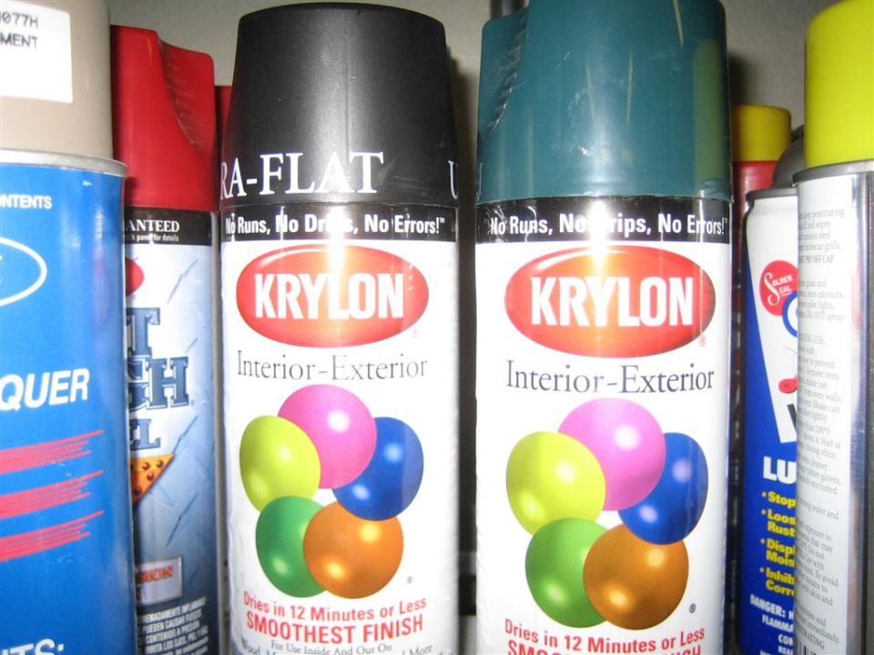 Krylon interior-exterior spray paint cans in flat black and teal on a shelf with other aerosols