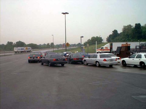 2000 Ford Crown Victoria - Multiple Ford Crown Victoria sedans are parked on a wet road, with a semi-truck visible in the distance.