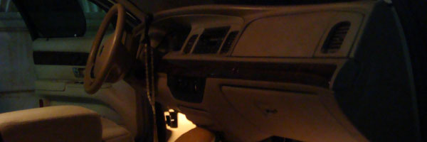 Dark wide-crop view of a tan car dashboard with woodgrain trim at night