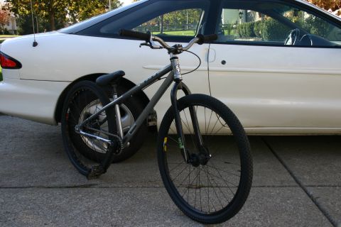 1997 Ford Probe - A bicycle is parked next to a white car on a paved surface.