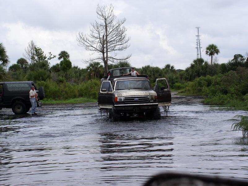 1991 Ford Bronco and Ford F-Series truck driving through water, doors open