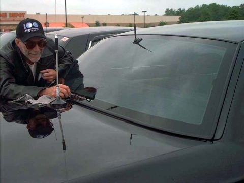 2000 Ford Crown Victoria - A man leans on the hood of a black 2000 Ford Crown Victoria, with another vehicle visible behind it.