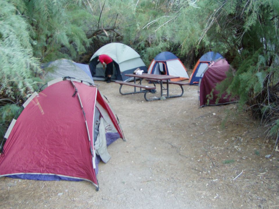 Several dome tents around a picnic table at a campsite
