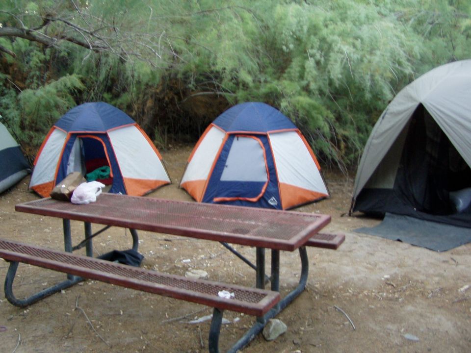 Two orange-and-blue dome tents behind a picnic table